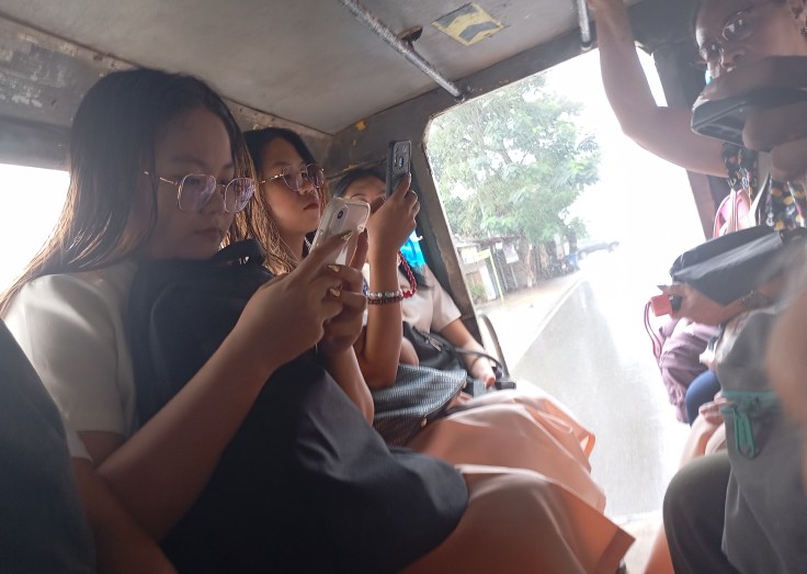 Riding the Jeepney going to Customs to clear out of Puerto Princesa. Schoolgirls doing social media studies. Photo Ray Penson