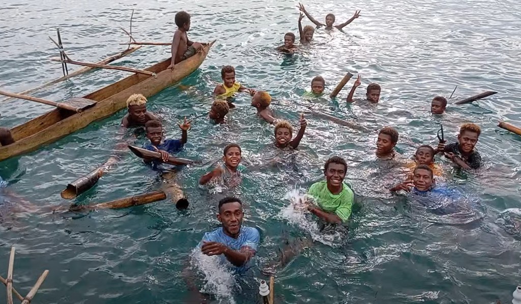 Children from the local school swam out to greet me, when the girls arrived it got even louder. Photo Ray Penson